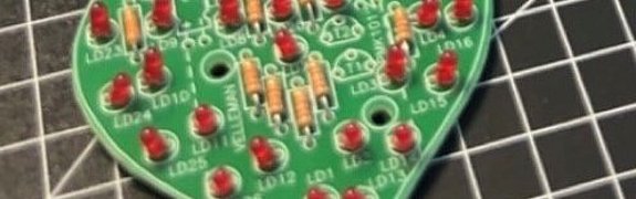 Ein herzförmiges elektronisches Bauteil, das beim PLATH Girls' und Boys' Day 2024 in Hamburg gelötet wurde, liegt auf einer Arbeitsfläche. Die Lötstellen sind sauber und deutlich sichtbar, und das fertige Bauteil strahlt einen Hauch von Stolz und handwerklicher Präzision aus. 